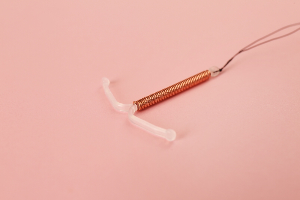 Copper,Intrauterine,Contraceptive,Device,On,Light,Pink,Background